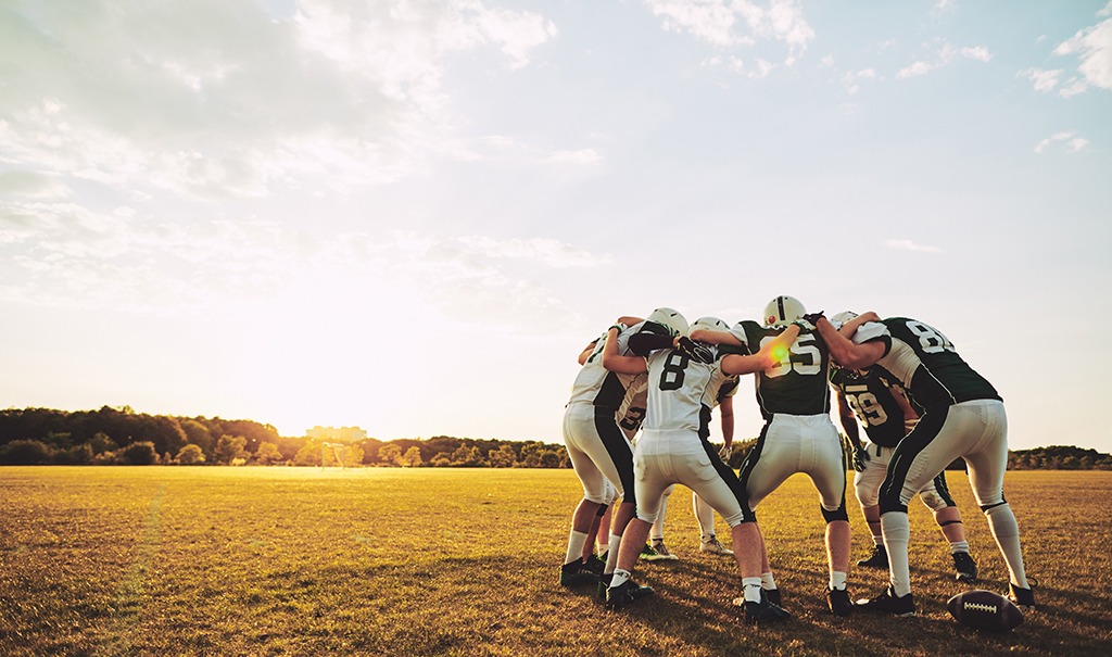 American Football Spieler umarmen sich in einem Kreis.