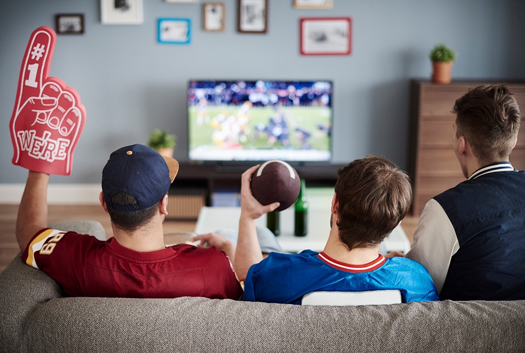 American Football Fans schauen gemeinsam ein American Football Spiel im Fernsehr.